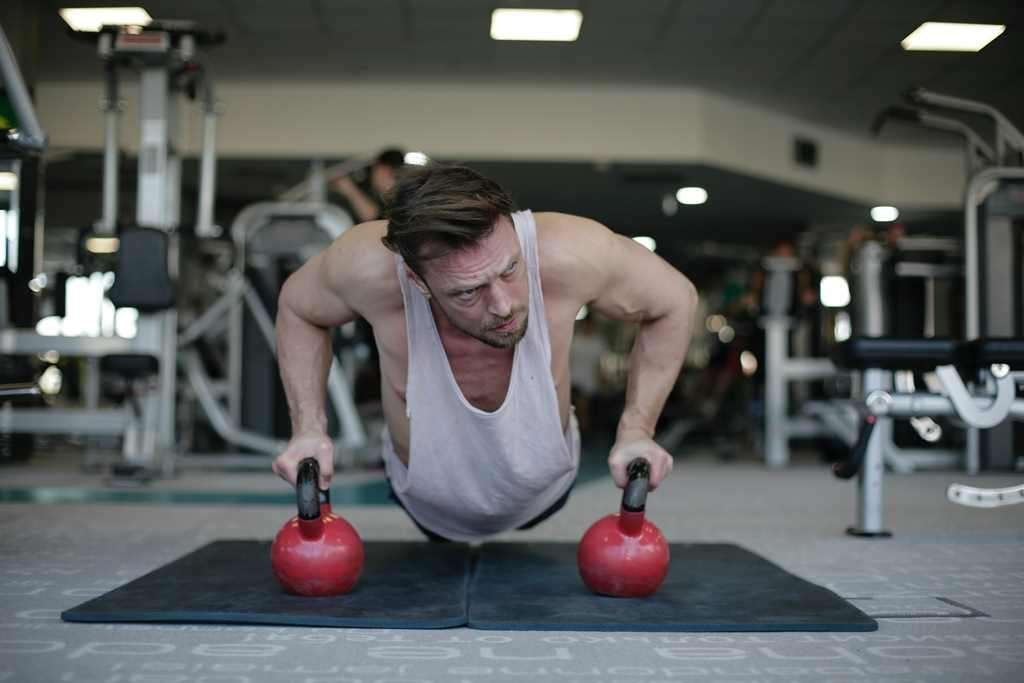 man doing push ups on handled weights